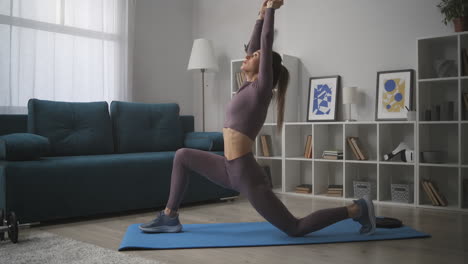young-woman-is-stretching-her-slender-body-during-morning-workout-training-in-living-room-in-apartment-sporty-and-healthy-lifestyle